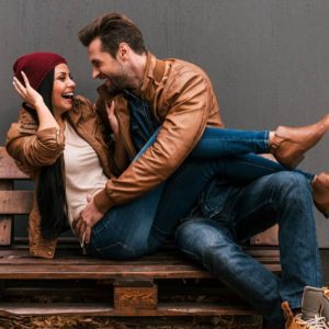 A man and woman sitting on a wooden bench.
