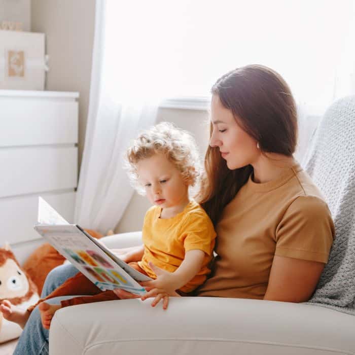 A stay at home mom reading a book to her child.