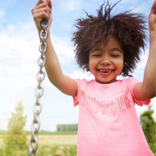 A little girl swinging on a swing.