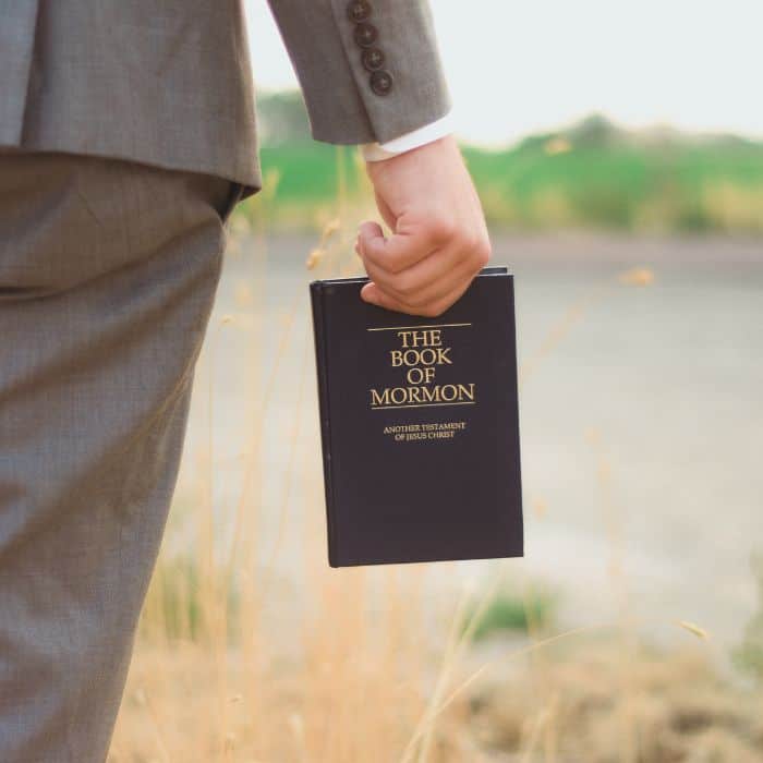 A young man holding a copy of The Book of Mormon.