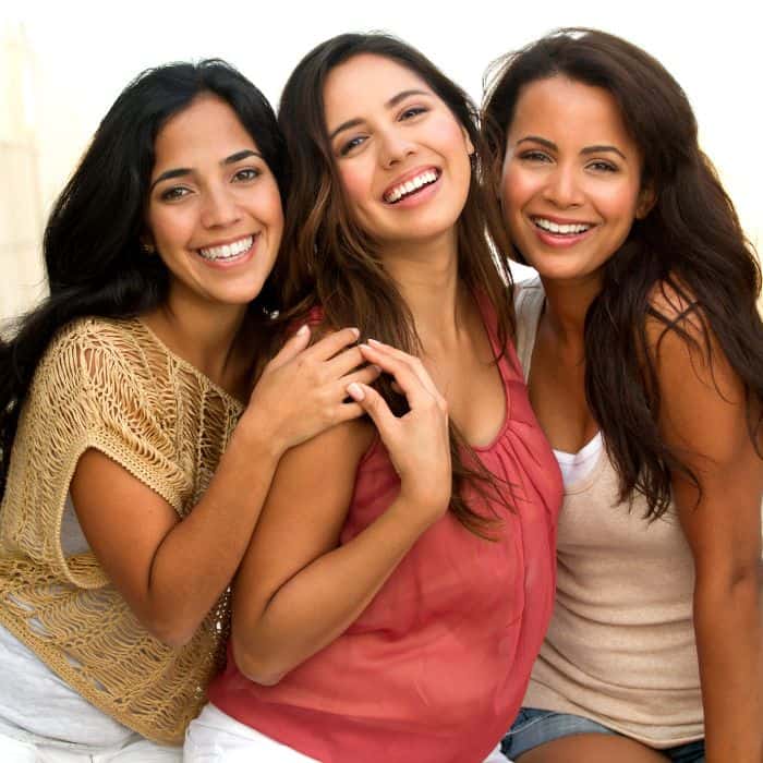 Three women are smiling with their picture being taken.