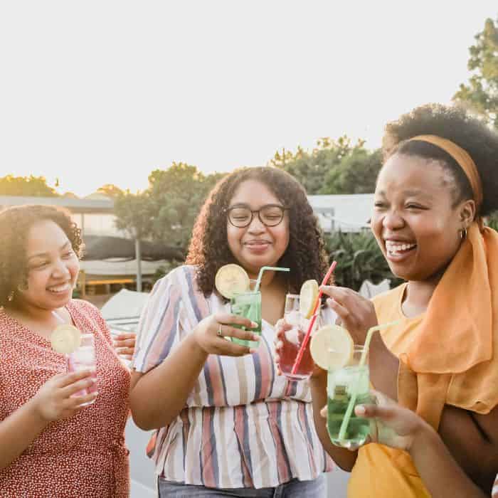 A group of women drinking tropical juice at a party. Everyone is smiling and laughing.