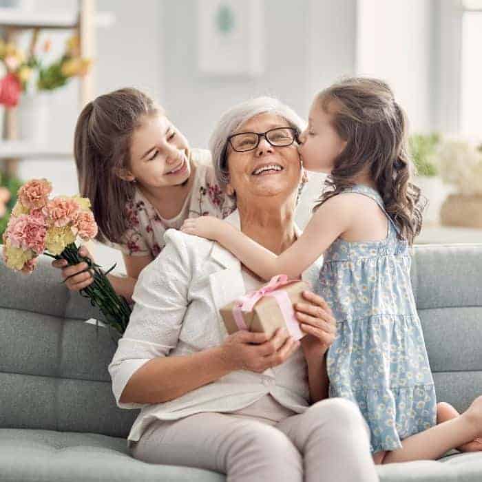 A grandmother with her two granddaughters. They are exchanging flowers and gifts.
