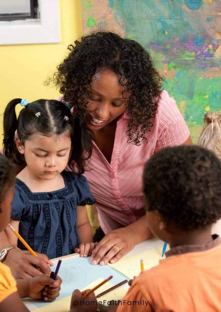 A daycare worker helping a young child with her writing.